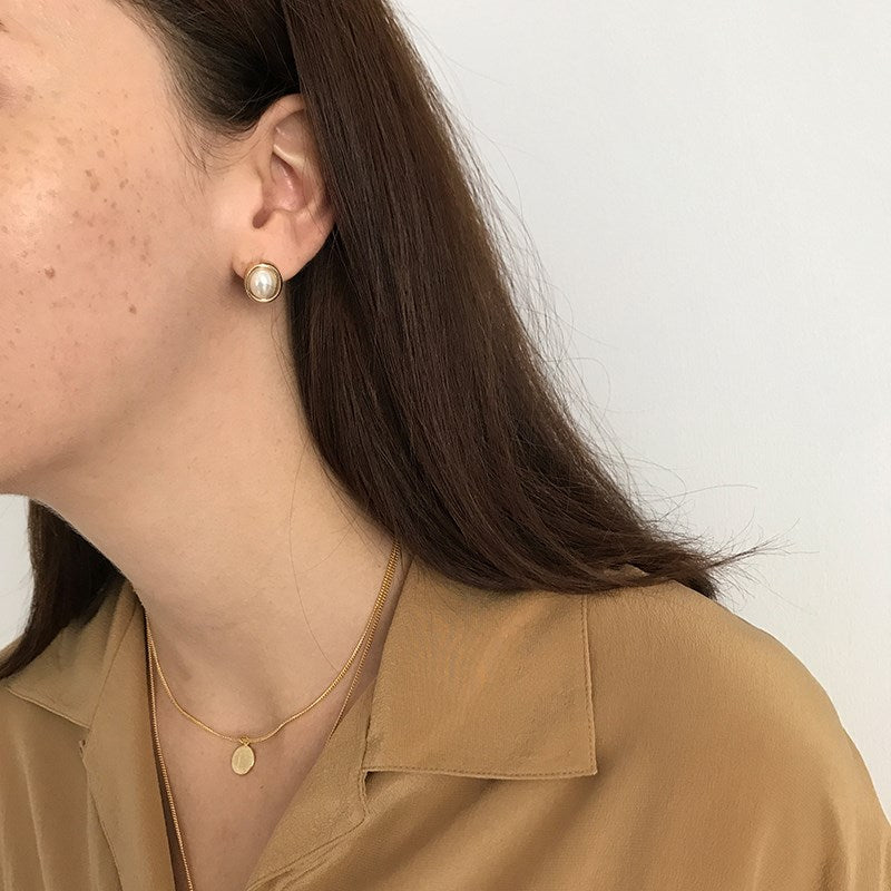 Oval pearl-style stud earrings with gold-tone rim