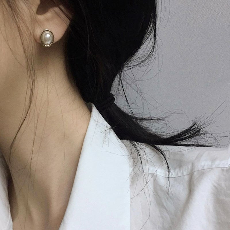 Oval pearl-style stud earrings with gold-tone rim