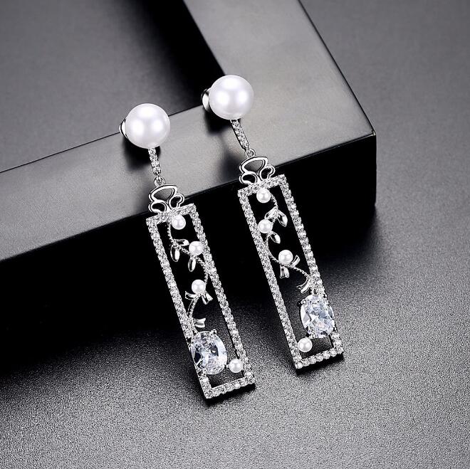 Long pearl-style drop earrings with decorated bar