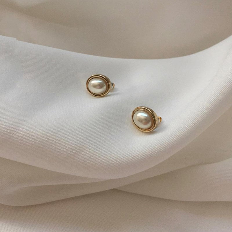 Oval pearl-style stud earrings with gold-tone rim