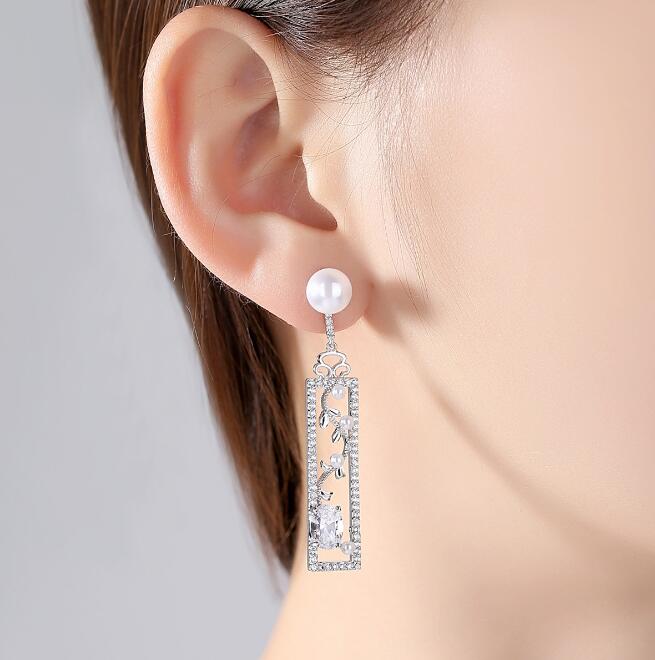 Long pearl-style drop earrings with decorated bar