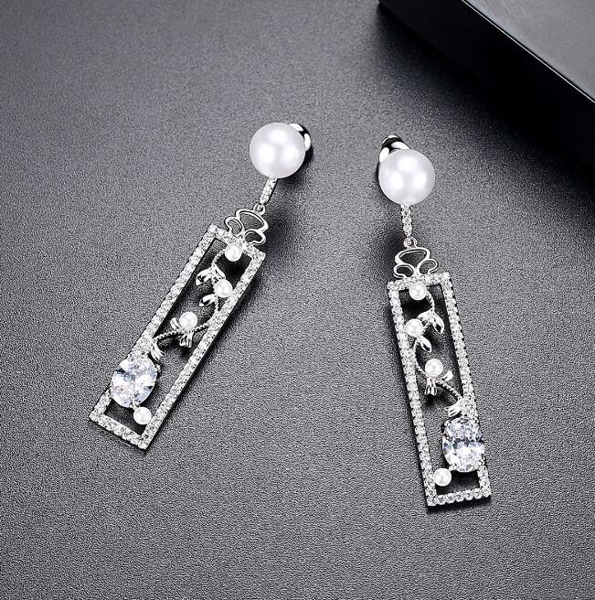 Long pearl-style drop earrings with decorated bar